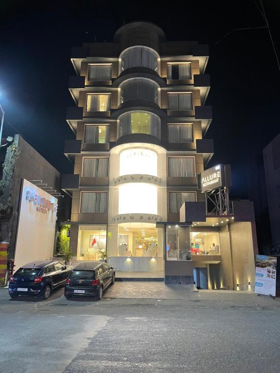 De Glance Hotel في سورات: سيارتين متوقفتين أمام مبنى في الليل