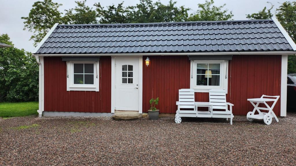 a red shed with two chairs in front of it at Tift bossgård in Linköping