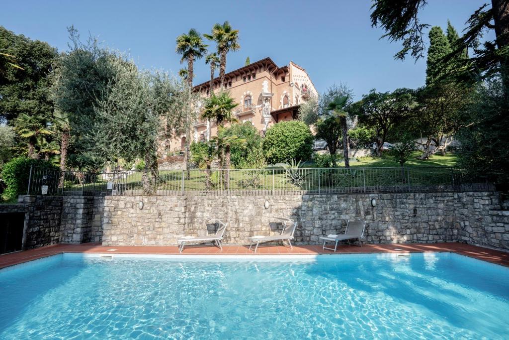 a swimming pool with two chairs and a building at Hotel Bellevue in Gardone Riviera