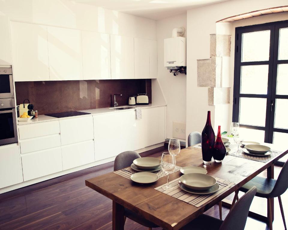 una cocina con una mesa de madera con platos y copas de vino en THE RIVERSIDE LODGE Cozy and spacious apartment en Girona