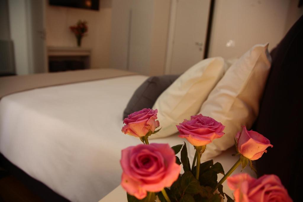 a vase of flowers on a table next to a bed at B&B Massimo Inn in Palermo