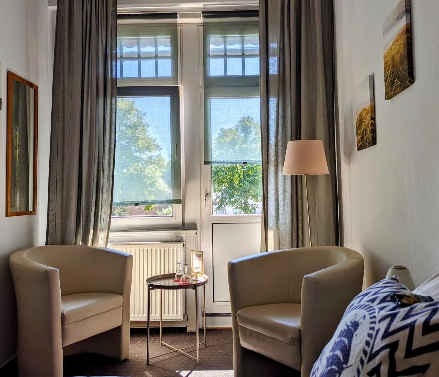 a bedroom with two chairs and a bed and a window at Hotel Schweizerhaus in Lübeck