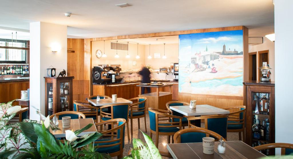 a restaurant with tables and chairs and a painting on the wall at Hotel Colorado Cesenatico in Cesenatico