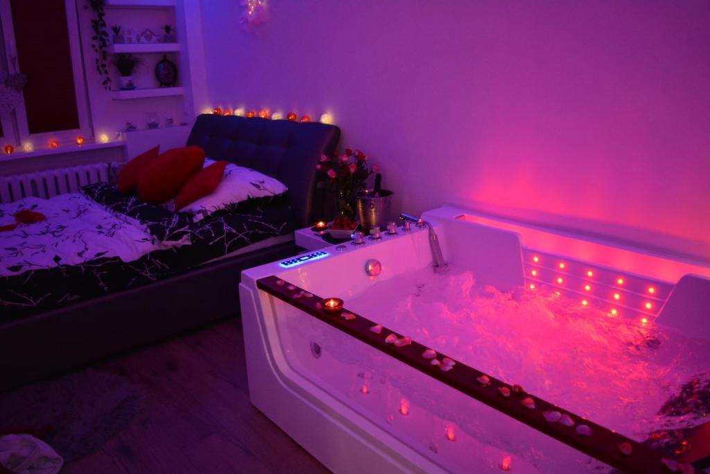 a purple room with a tub and a bed at Jacuzzi Apartament in Toruń
