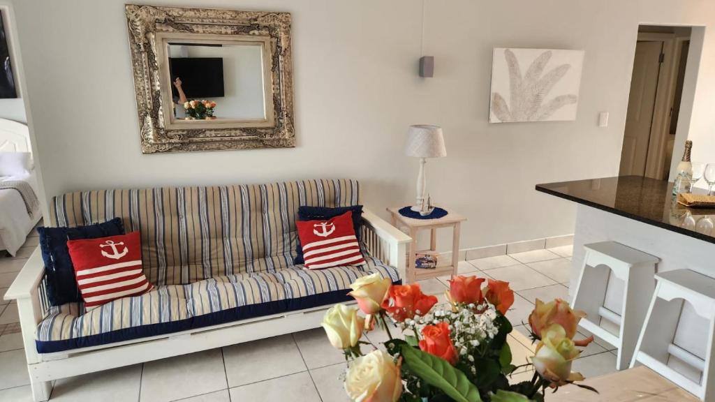 a living room with a couch and a table with flowers at Stylish Hartenbos Apartment in Mossel Bay