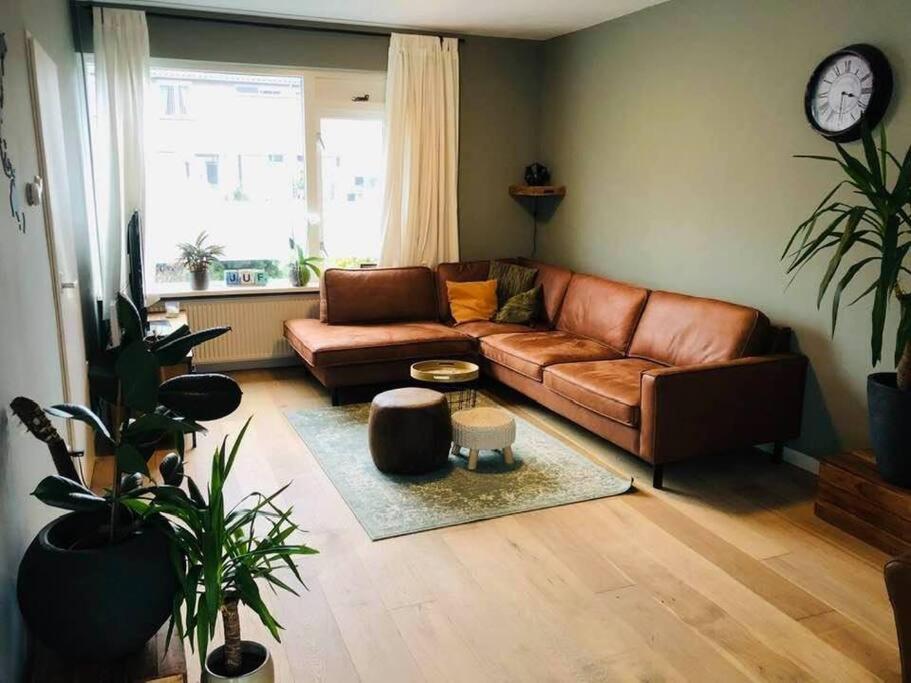 sala de estar con sofá de cuero marrón y reloj en Compleet huis in Nijmegen, en Nijmegen