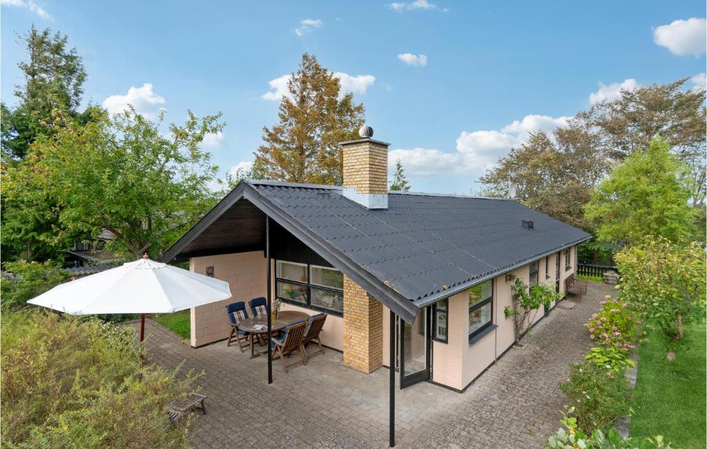 a house with a black roof with a table and an umbrella at Nice Home In Vejby With Kitchen in Vejby