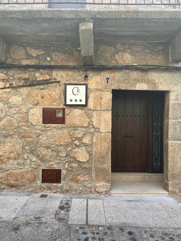 a stone building with a door and a clock on it at Casa Rural De Mascoras in Santibáñez el Alto