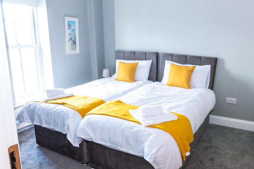 Cama grande con sábanas y almohadas amarillas y blancas en Castle gate lodge en Derry
