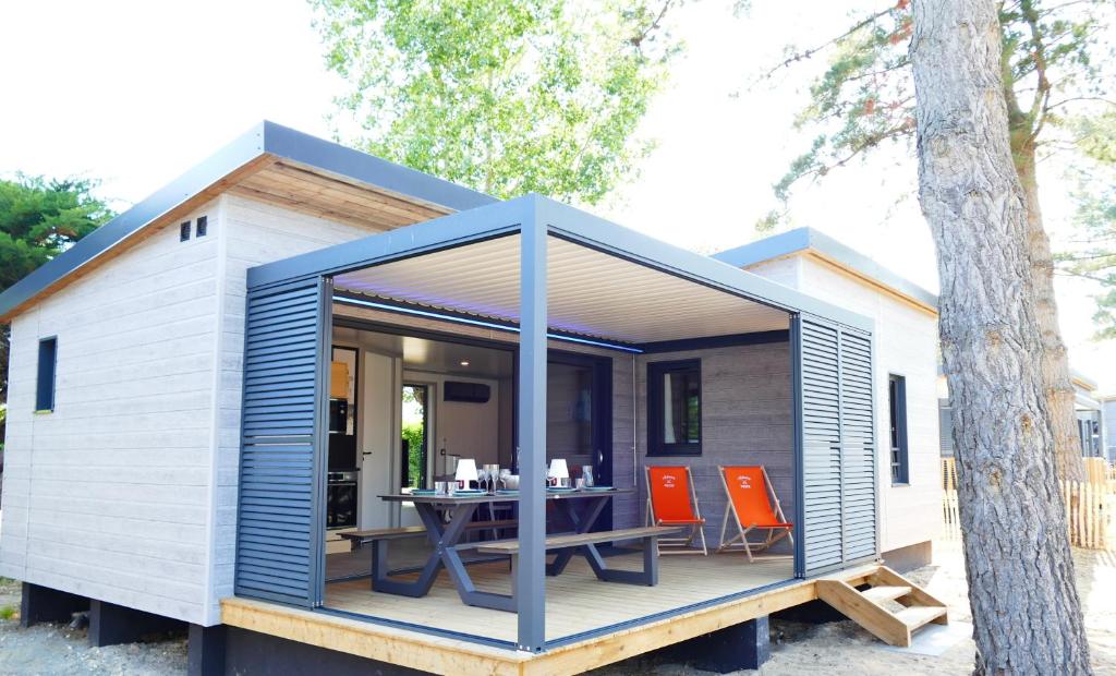 a tiny house with a table and chairs on a deck at Escales Voyages Cottage des Dunes - Chalet de 49m2 climatisé - 6 personnes in Jullouville-les-Pins