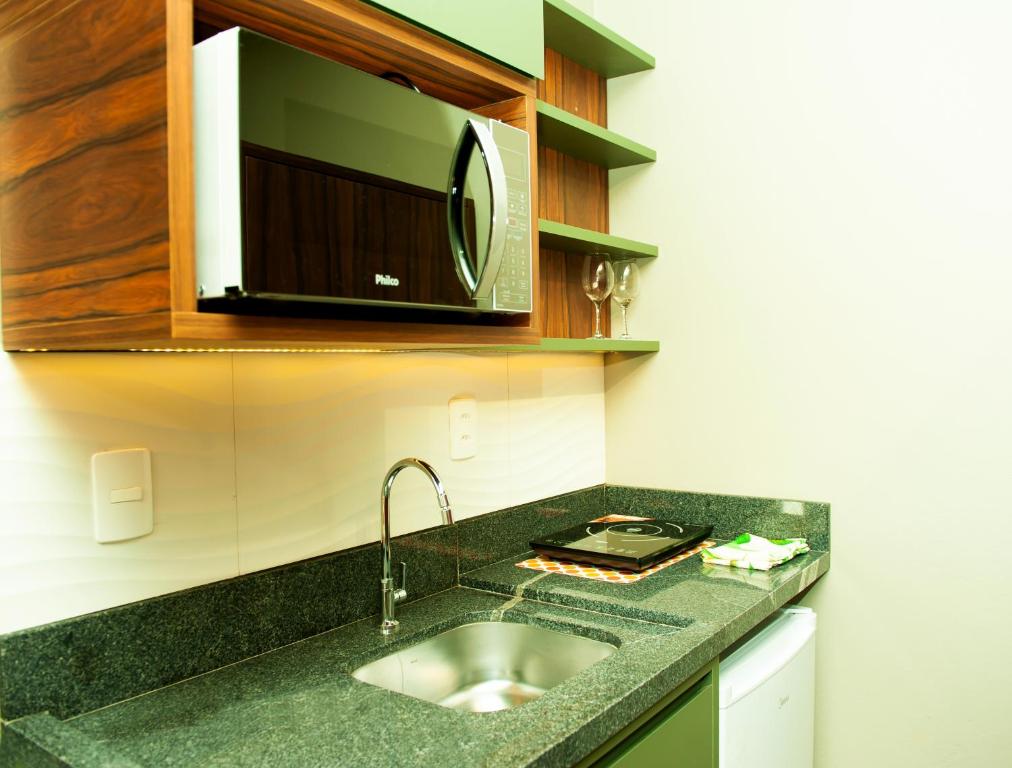 a kitchen counter with a sink and a microwave at HOSPEDAGEM CASA COMPACTA in Jaraguá do Sul