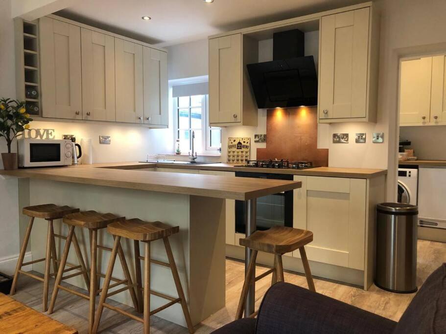 a kitchen with a large island with bar stools at The Cottage, amazing views, pet friendly in Heswall