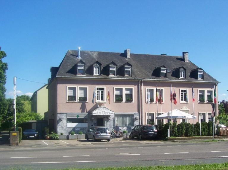 une grande maison avec des voitures garées devant elle dans l'établissement Hotel Am Ufer, à Trèves