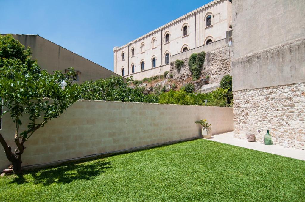 a garden with a retaining wall and green grass at Intalloi in Noto