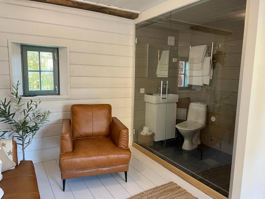 uma casa de banho com uma cadeira de couro e um WC. em Suloinen luhtirakennus Randla em Rauma