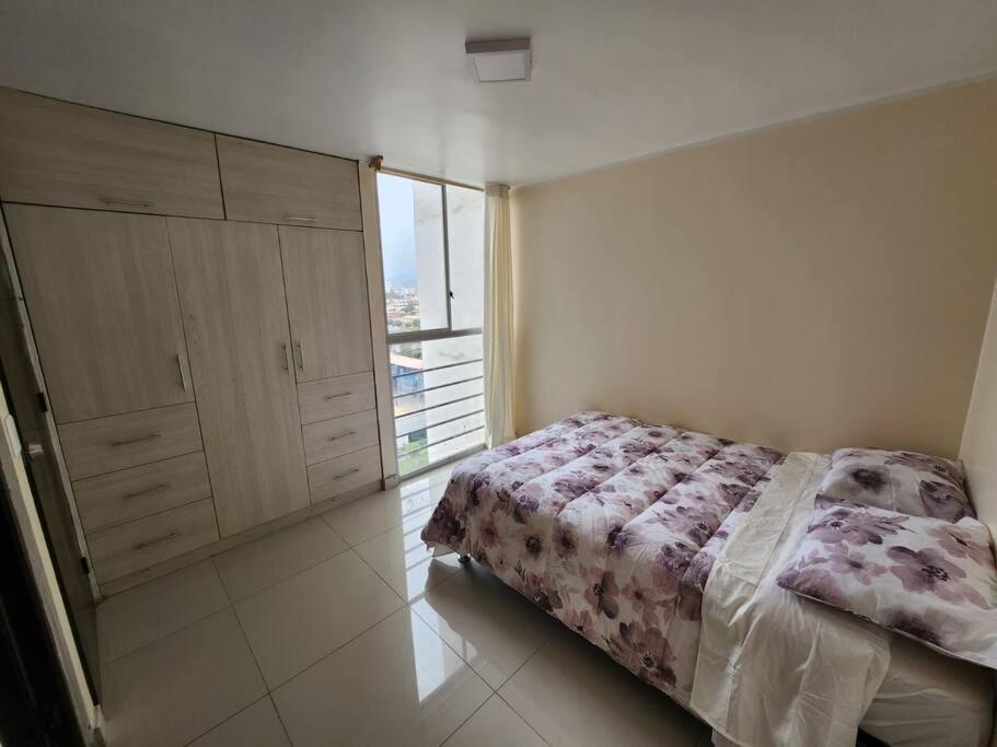 a bedroom with a bed and a large window at Departamento amplio y acogedor San Miguel in Lima