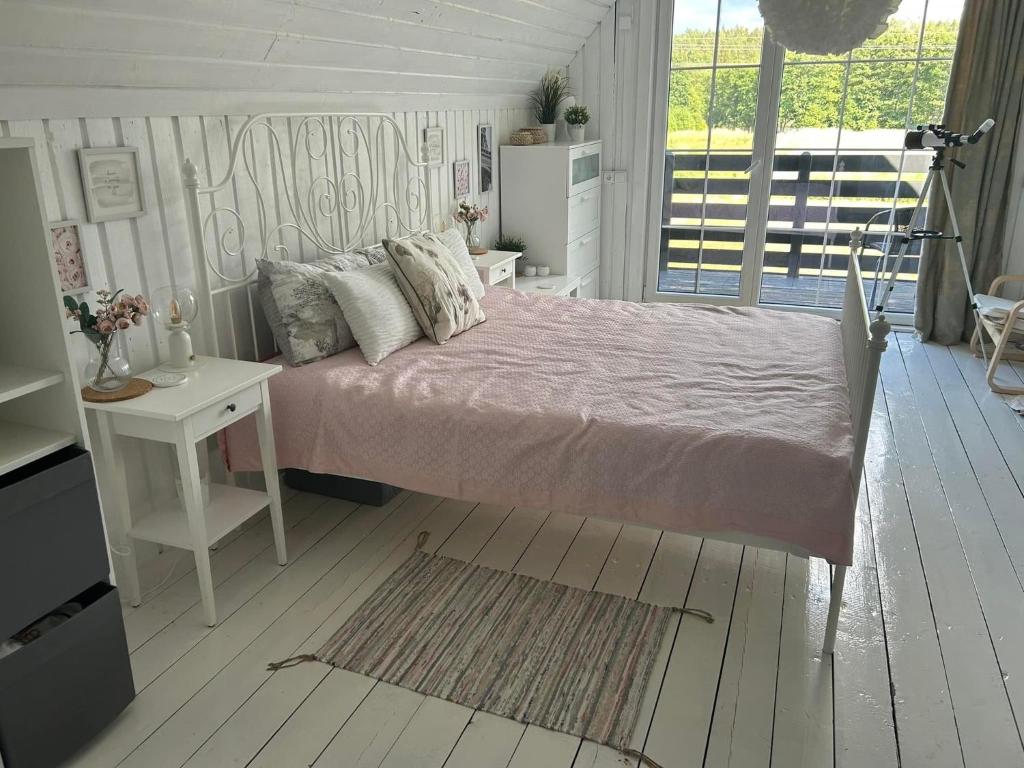 Schlafzimmer mit einem Bett, einem Tisch und einem Fenster in der Unterkunft Sodyba ramiam poilsiui in Kaltanėnai