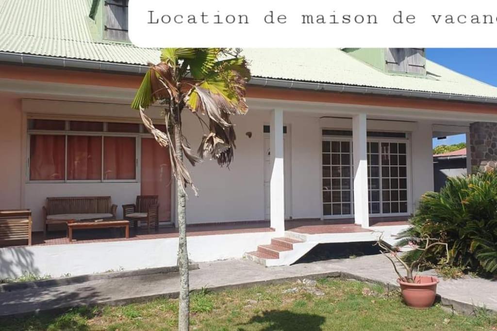 a house with a palm tree in front of it at La Villa Ti-Louise à Marie-Galante in Grand-Bourg