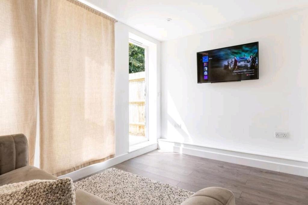 ein Wohnzimmer mit einem TV an der Wand in der Unterkunft Gorgeous London Town House Sleeps up to 8 in London