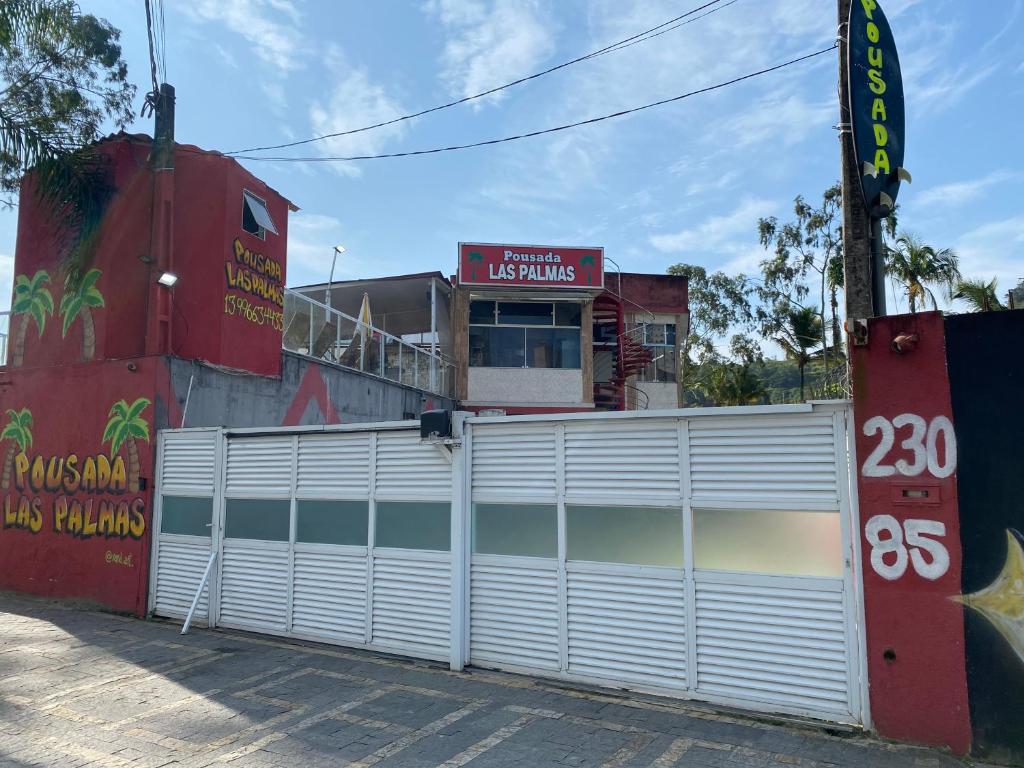 porta bianca del garage di fronte a un edificio di Pousada Las Palmas a Guarujá