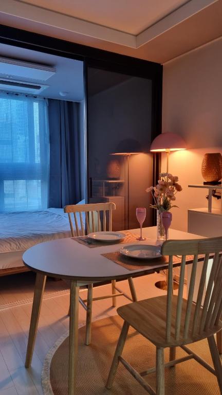 um quarto com uma mesa e cadeiras e uma cama em Mia House em Daegu