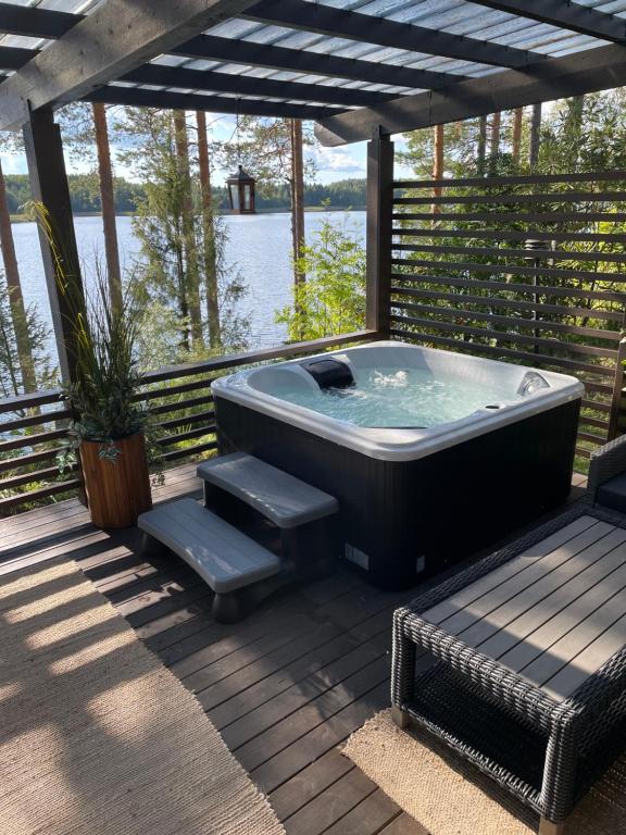 un bain à remous installé sur une terrasse avec un banc dans l'établissement Cityvilla on the shore of Lake Haapajärvi, à Joensuu