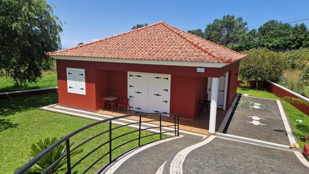 a small red building with white doors and a staircase at Vila Henrique Country Cottage in Fajã da Ovelha