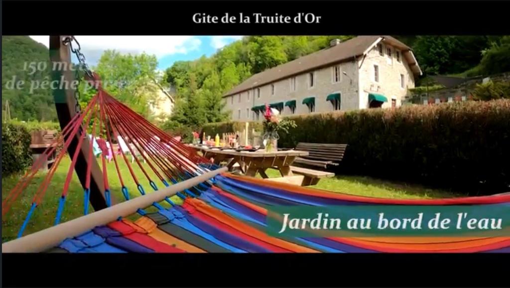 eine Hängematte im Hof mit einem Tisch und einem Gebäude in der Unterkunft Gîte La Truite d’Or in Lods
