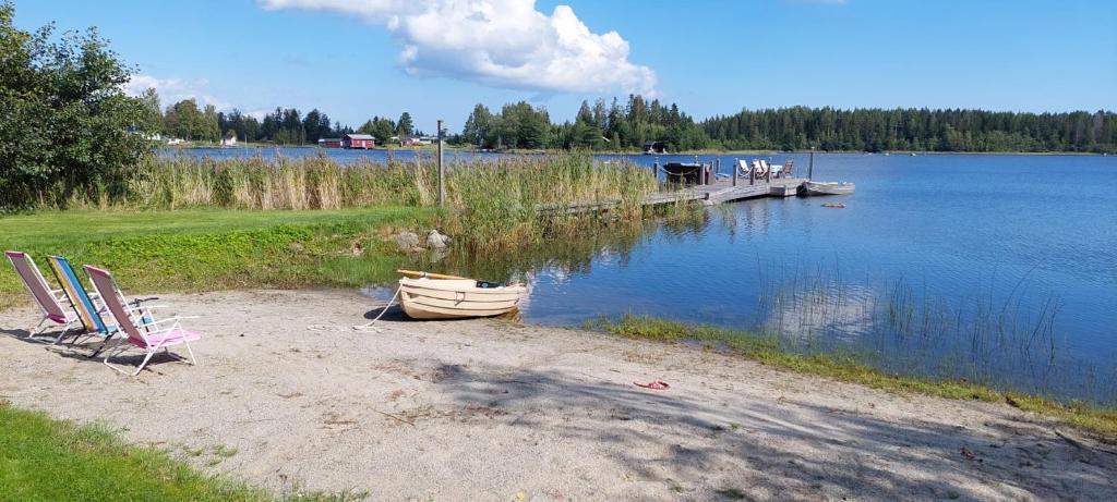 una playa con 2 sillas y un barco en el agua en Timber house with private beach and boat including. en Njurundabommen