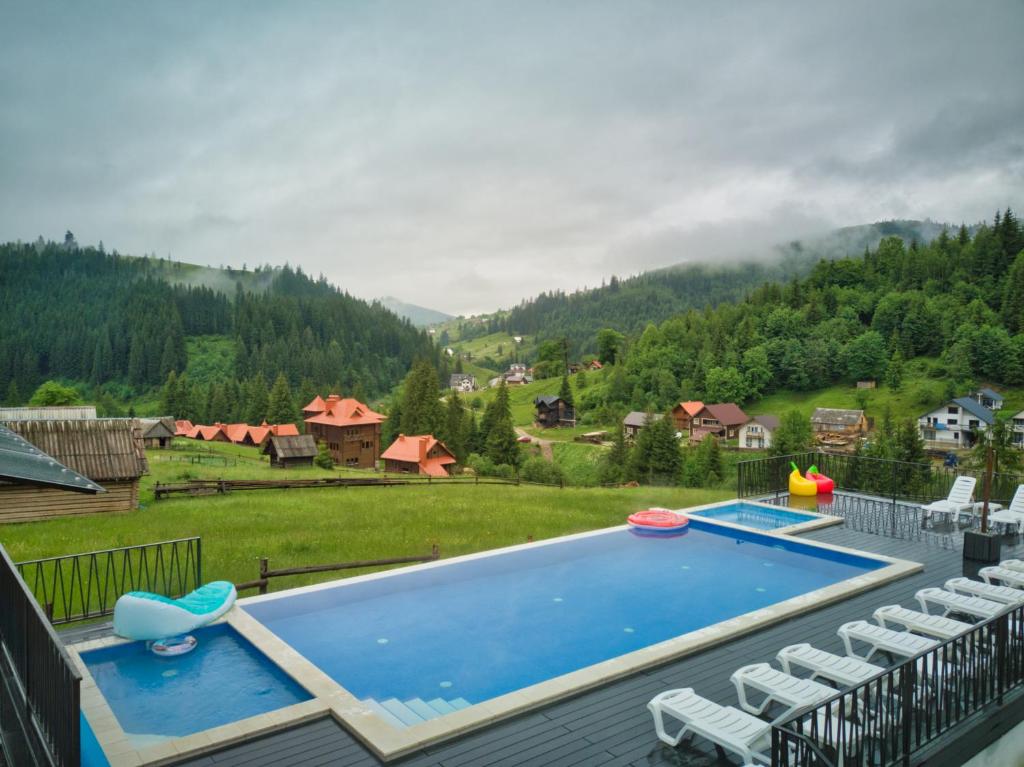 a swimming pool with chairs and a view of a mountain at Nikol Guest House in Bukovel