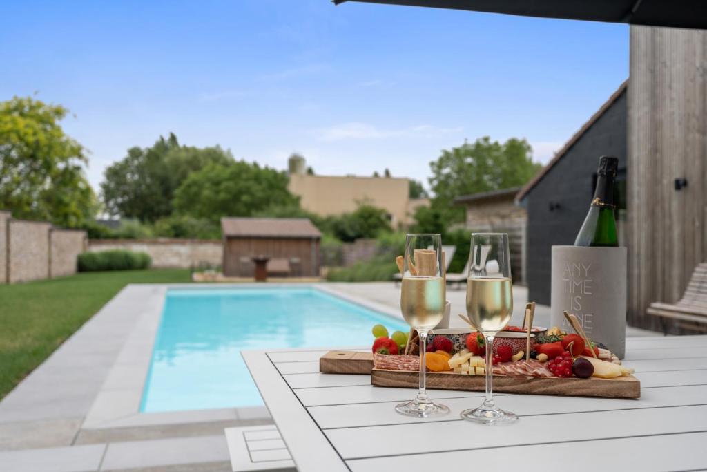 a table with two glasses of wine and a basket of fruit at Maison Arthur vakantiewoning met verwarmd zwembad in Lo-Reninge