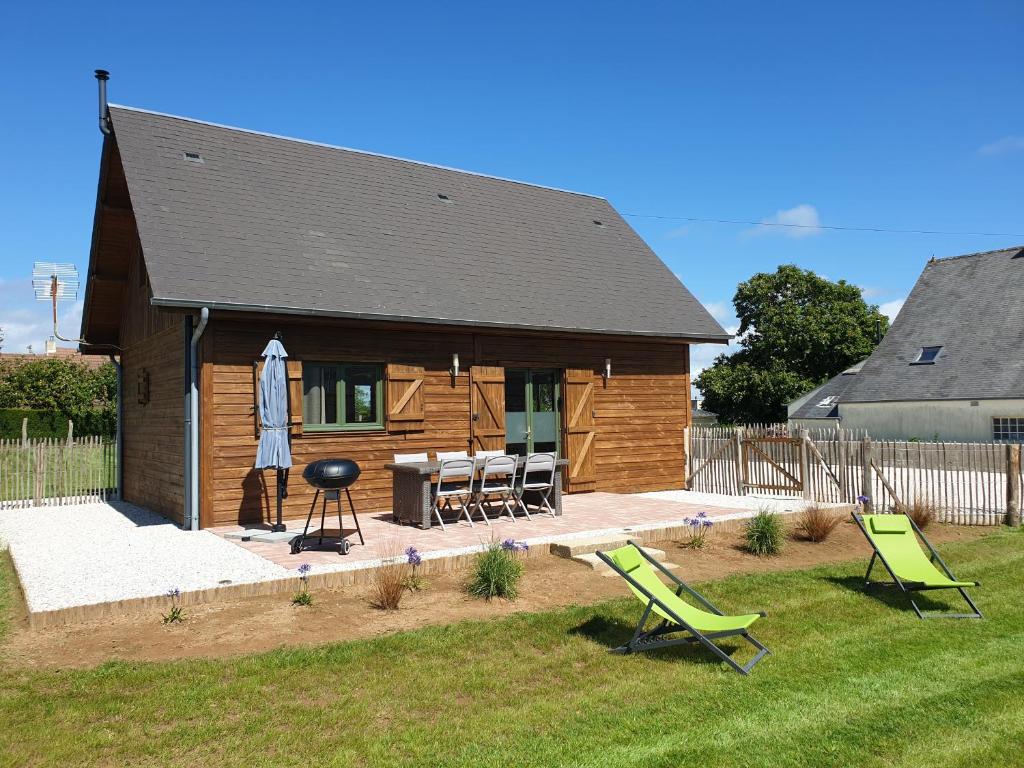 eine Blockhütte mit zwei Gartenstühlen und einem Grill in der Unterkunft LE CHALET in Saint-Pierre-dʼArthéglise