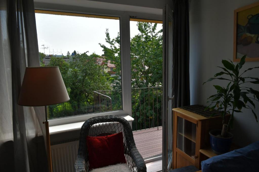 a chair with a red pillow sitting in front of a window at Przytulne duże mieszkanie w domku jednorodzinnym in Koszalin