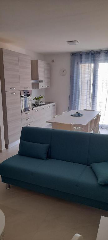 ein Wohnzimmer mit einem blauen Sofa und einer Küche in der Unterkunft Appartamento garibaldi in San Benedetto del Tronto