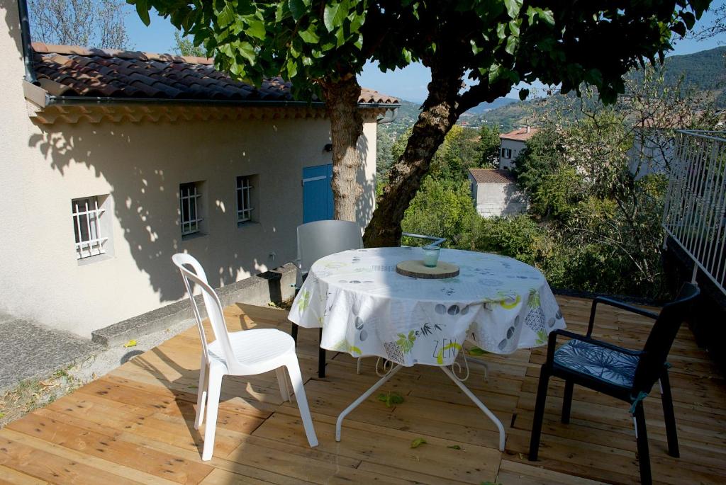 a white table and chairs on a wooden deck at Nid douillet - LES FARGETTES - superbe vue - charmante petite maison avec jardin - 2 pièces à Privas in Privas