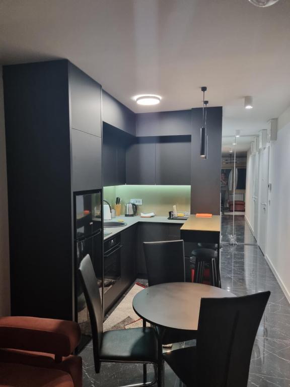 a kitchen with black cabinets and tables and chairs at One bedroom apartment in Belgrade city center in Belgrade