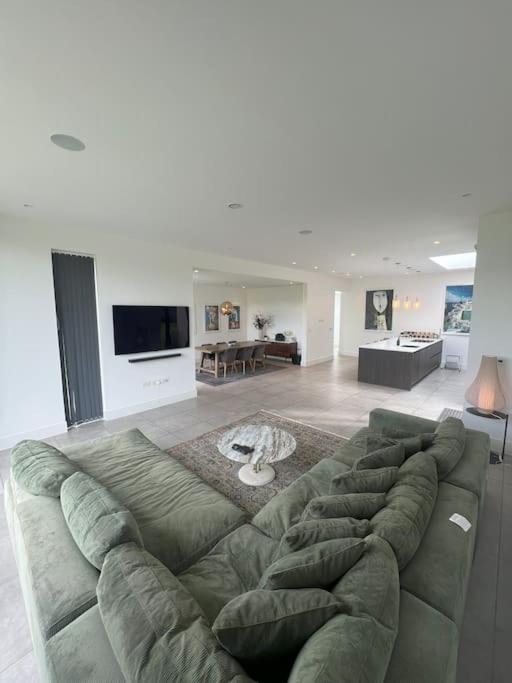 a living room with a large green couch at Stunning Luxury in Central Alderley Edge in Alderley Edge