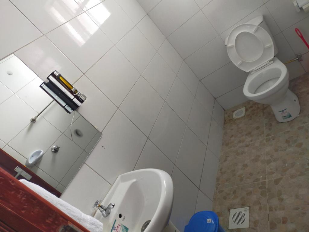 ein weißes Bad mit WC und Urinal in der Unterkunft Joy Fully furnished Apartments in Nairobi