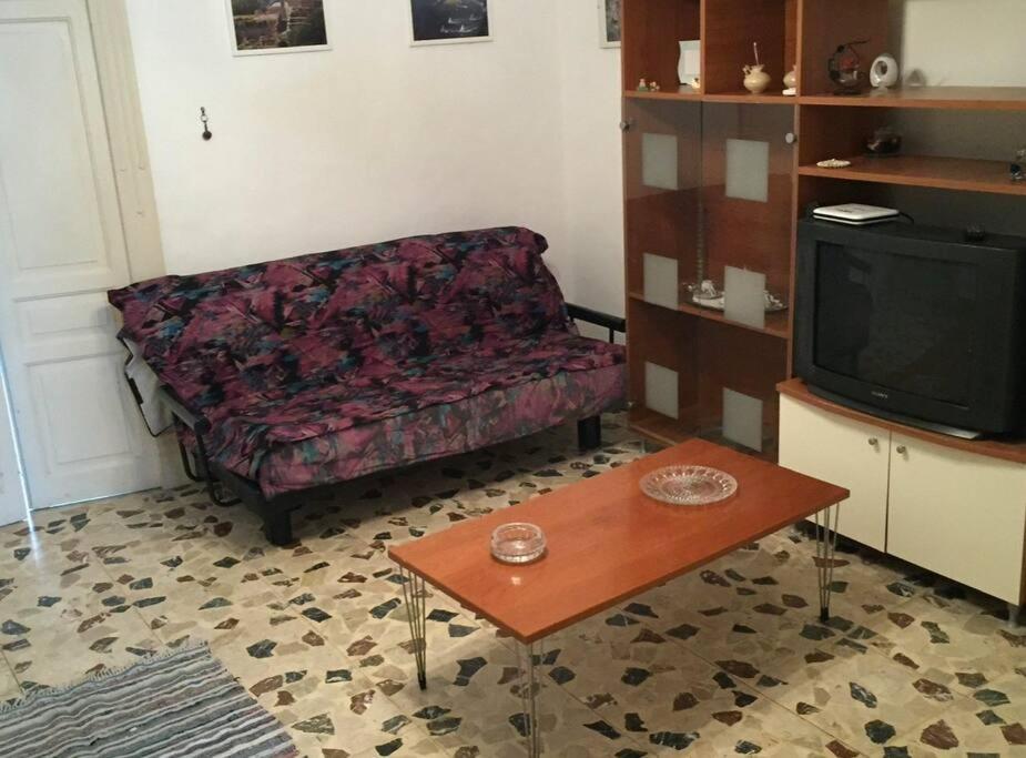 a living room with a couch and a table and a tv at Vittorio Emanuele apartment in Canicattini Bagni