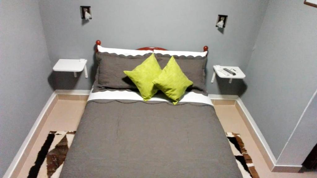 um quarto com uma cama com duas almofadas amarelas em Hostal El Farolito em Humahuaca