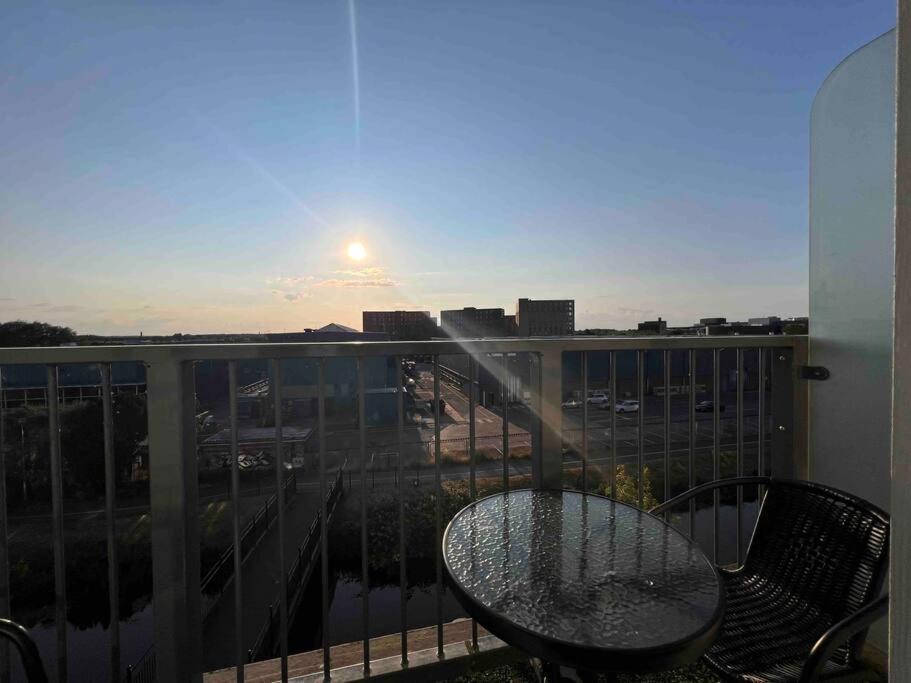 einen Glastisch und Stühle auf einem Balkon mit Blick auf den Sonnenuntergang in der Unterkunft Lincoln View. Sleeps 6. Balcony. Self check-in. in Lincolnshire