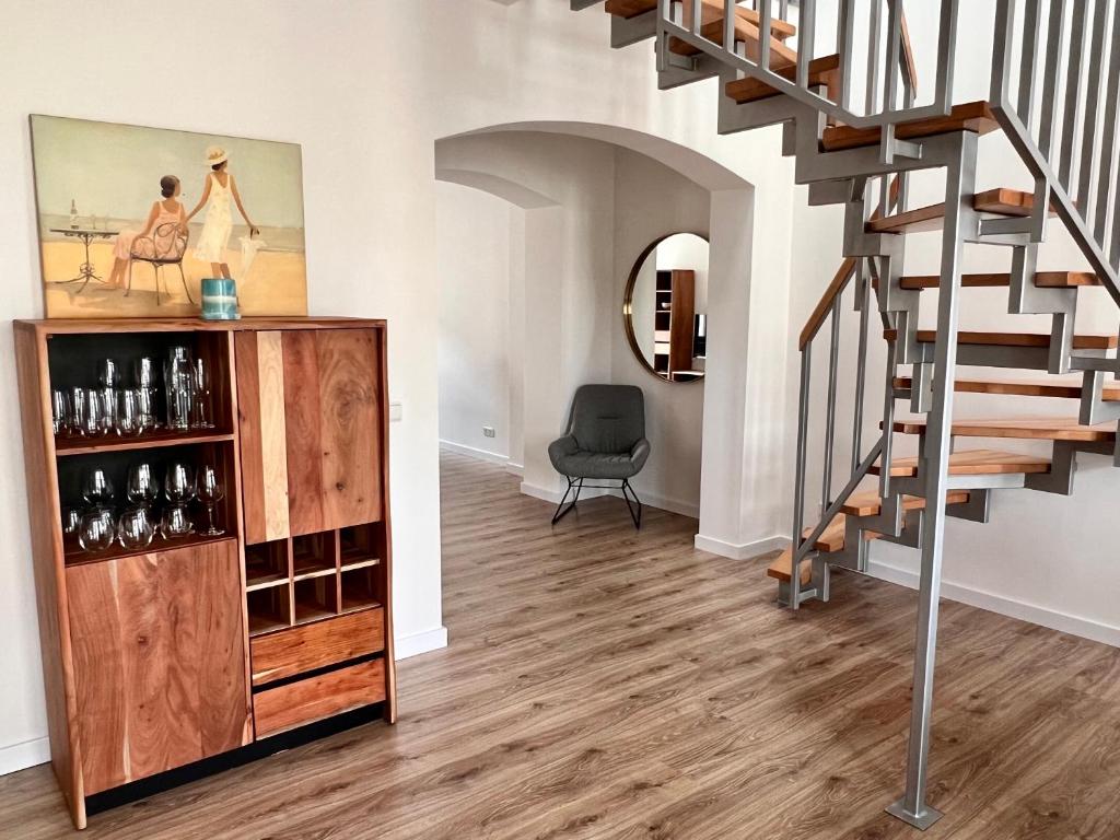 een woonkamer met een trap en een wijnkast bij Apartment Kander in Görlitz