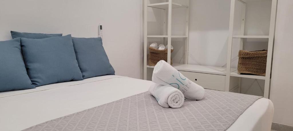 a white bed with blue pillows on top of it at Sabbia Suites Varadero in Puerto del Carmen
