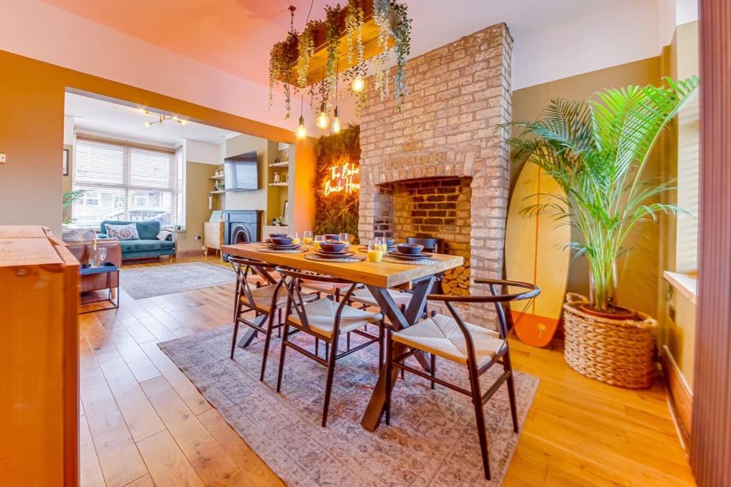 a dining room with a table and a brick fireplace at Boho Beach House: Hot Tub in Cleethorpes