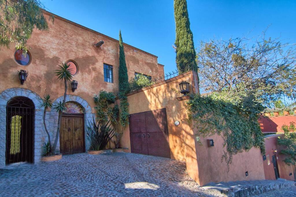 a large brick building with a gate and a garage at Casa Puesta del Sol w/views slps 8 3 bths 3 bed in San Miguel de Allende