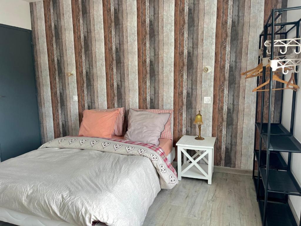 a bedroom with a bed and a striped wall at Nid douillet à La Bresse in La Bresse