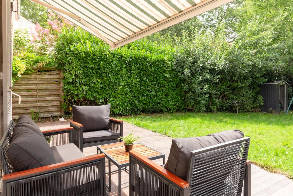 a patio with chairs and a table and a hedge at Maison Le Garden - Jardin BBQ - 4 Chambres 8 Pers - RER A Paris Direct in Cergy