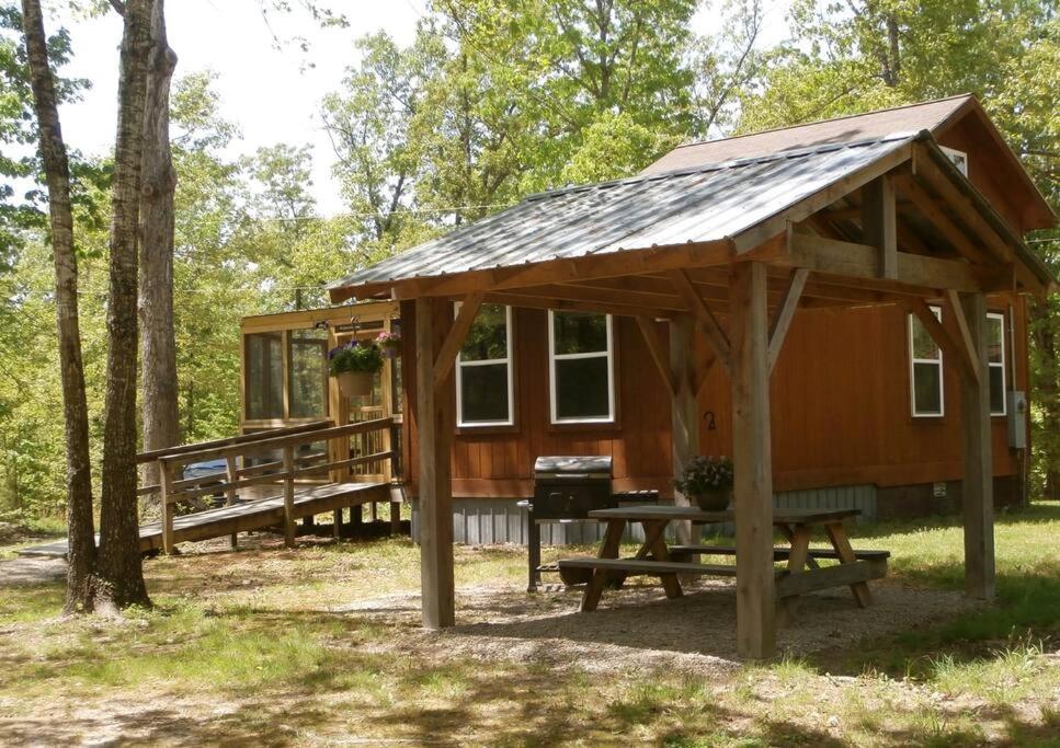 a cabin in the woods with a picnic table and a grill at Redbud Cottage in Maumee
