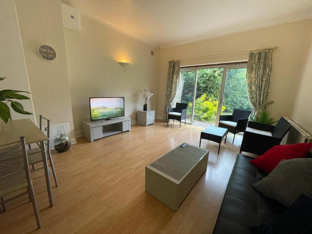 a living room with a couch and a tv at Elegant Weybridge Apartment near Train Station in Oatlands Park