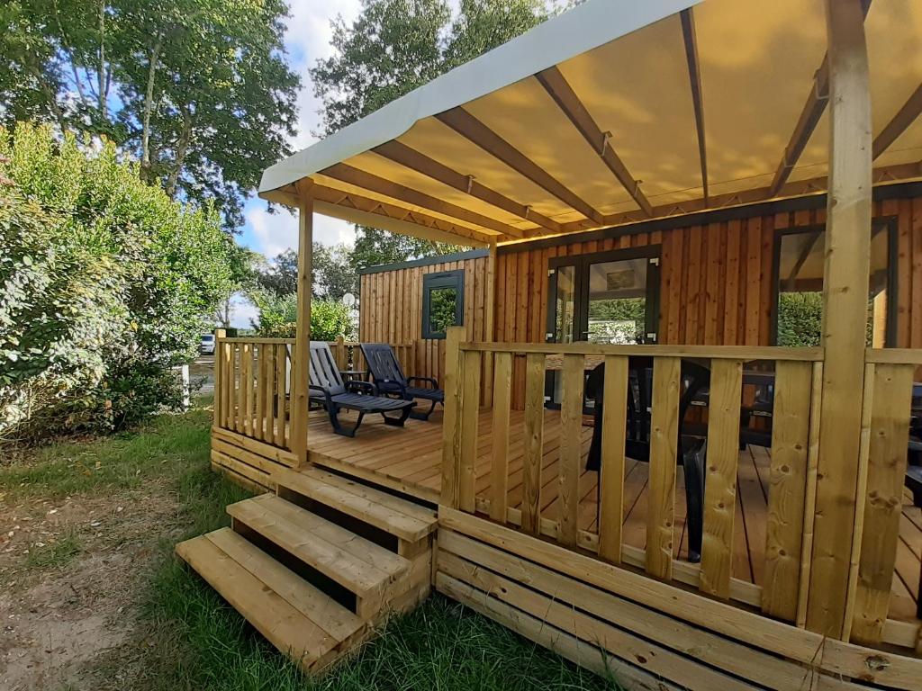 a wooden cabin with a deck with a bench at Chez Laura et Cyril in Gujan-Mestras